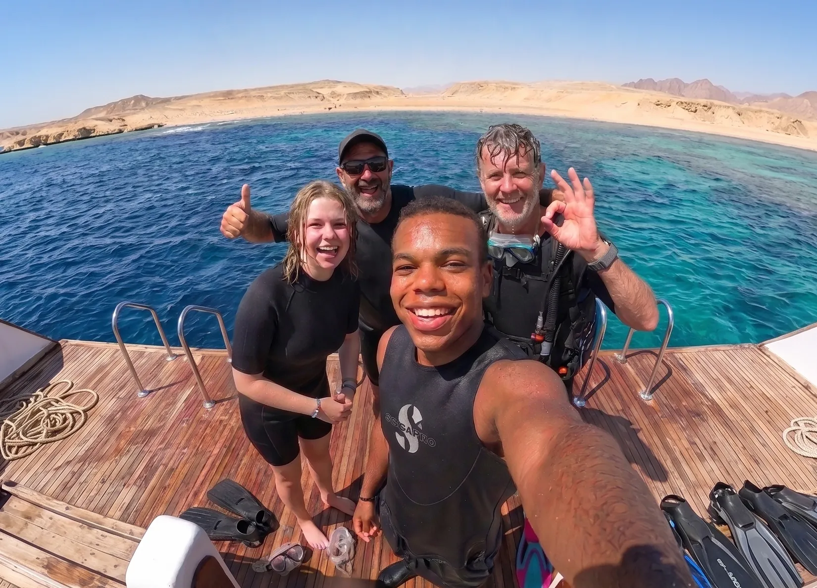 Four divers smiling on a DiveRED boat after a Red Sea day trip
