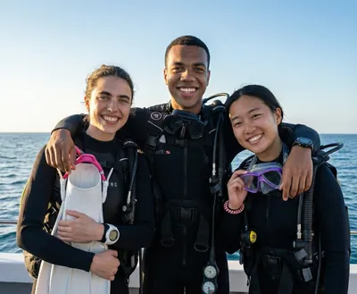 Three newly certified divers smiling on the dive boat in Hurghada, Red Sea